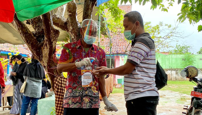 Salah satu pemilih saat masuk ke TPS 10 Pangarangan di sterilkan terlebih dahulu
