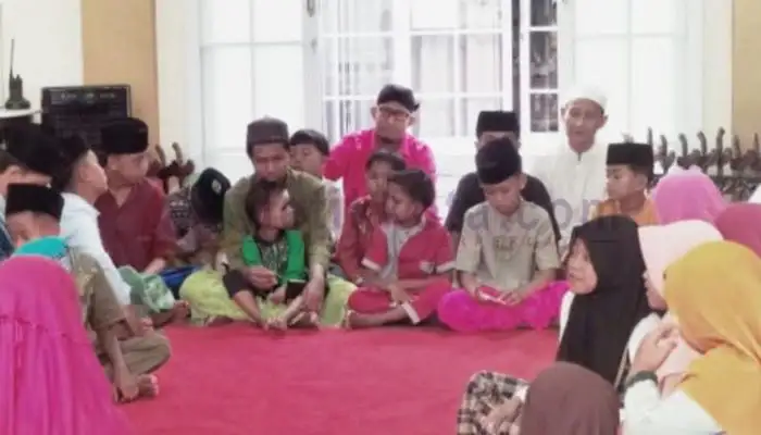 Bupati Sumenep Achmad Fuzi (blangkon hitam) duduk dan bercanda di antara anak yatim di kediamannya Desa Torbang Kecamatan Batuan.