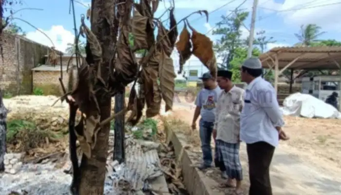 Pengurus MWC NU Lenteng Sumenep melihat sisa bekas pembakaran kayu bahan bangunan kantornya.