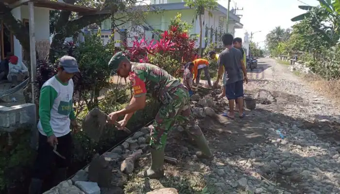 Babinsa Serda Moh. Fausi bersama warga gotong royong memperbaiki jalan di Desa Tegalharjo, Kecamatan Glenmore, Kabupaten Banyuwangi.