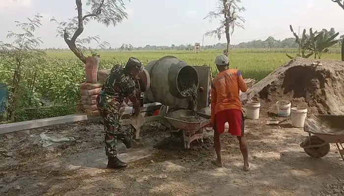 Babinsa Desa Puro, Koramil 02/Karangmalang, Kodim/0725, Serda Dwi Nurmawoko membantu warga mengecor jalan kampung.