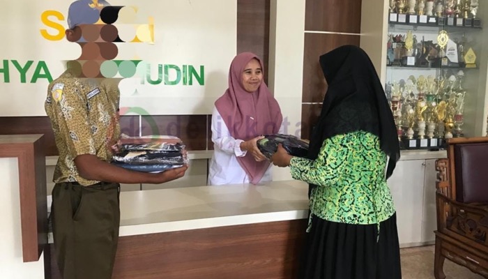 Salah seorang siswi baru menerima bantuan seragam gratis dari SMKN Ihya'ulumuddin, Desa Padang, Kec. Singonjuruh, Kab. Banyuwangi.