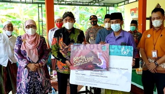 Bupati Sumenep, H. Achmad Fauzi Wongsojudo didampingi Wabup Hj. Dewi Khalifah menyerahkan bantuan bagi guru ngaji.