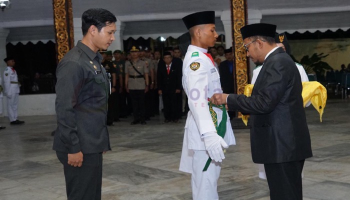 Bupati Sumenep, H. Achmad Fauzi Wongsojudo memasang kendit secara simbolis dalam pengukuhan Paskibraka 2023.
