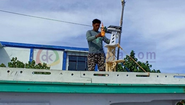 Seorang nelayan memasang SIKapal pada perahu miliknya sebelum berlayar.