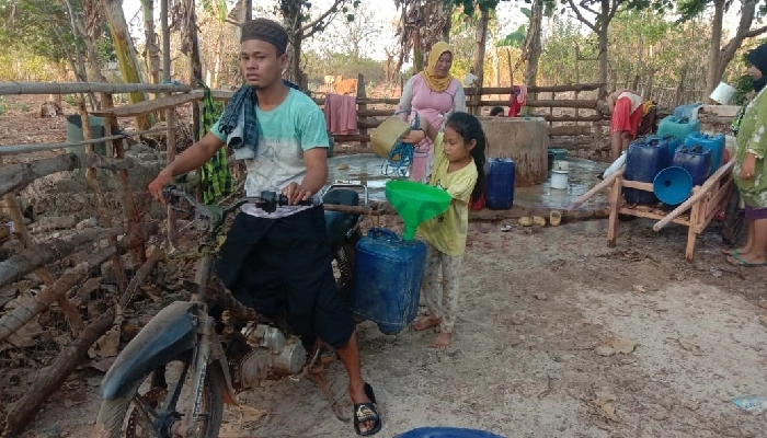 Warga Desa Saur Saebus harus naik motor untuk mengambil air di sumur kampung sebelah.