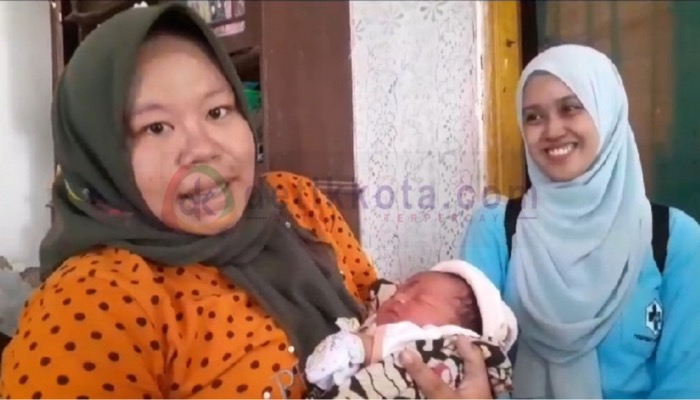 Ibu Surayya menggendong bayi yang dilahirkannya di tengah pegunungan bersama Bidan Monique Marthalitha (kanan).