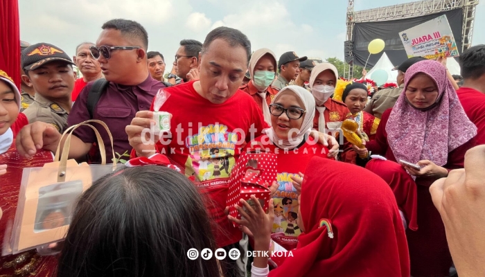 Eri Cahyadi Wali Kota Surabaya dan Rini Indriyani istrinya saat menerima hadiah dari anak-anak di perayaan Hari Anak Nasional di Tugu Pahlawan, Kamis (21/8/2025).