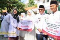 Bupati Banyuwangi Ipuk Fiestiandani menyerahkan insentif kepada perwakilan guru ngaji saat upacara peringatan Hari Santri Nasional 2025 di halaman Kantor Bupati Banyuwangi.