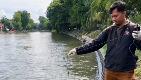 Petugas Dinas Lingkungan Hidup (DLH) Kota Surabaya saat mengambil sampel air di saluran Banyu Urip untuk uji kualitas air.