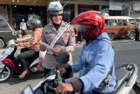 Personel Satlantas Polres Sumenep memberikan edukasi keselamatan berlalu lintas dan membagikan brosur Operasi Zebra 2025 kepada pengunjung Pasar Tumpah Prenduan, Rabu (19/11/2025).