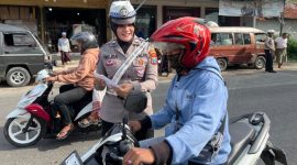 Personel Satlantas Polres Sumenep memberikan edukasi keselamatan berlalu lintas dan membagikan brosur Operasi Zebra 2025 kepada pengunjung Pasar Tumpah Prenduan, Rabu (19/11/2025).