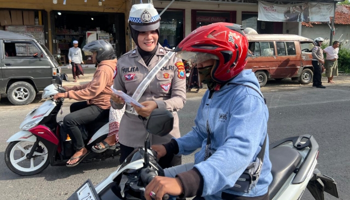 Personel Satlantas Polres Sumenep memberikan edukasi keselamatan berlalu lintas dan membagikan brosur Operasi Zebra 2025 kepada pengunjung Pasar Tumpah Prenduan, Rabu (19/11/2025).