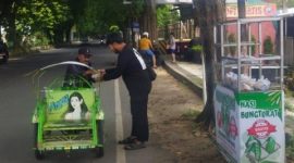 Anggota Komunitas Berbagi Sumenep (KBS) membagikan nasi bungkusan kepada pengendara dan pejalan kaki di simpang tiga Polres Sumenep, Jumat (26/12/2025).