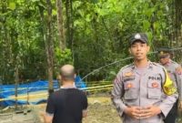 Petugas kepolisian memasang garis polisi di lokasi sumur bor yang mengeluarkan gas di Desa Planggaran Timur, Kecamatan Banyuates, Kabupaten Sampang.