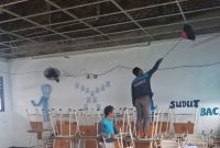 Petugas membersihkan puing plafon ruang kelas SMPN 60 Surabaya yang runtuh akibat tekanan angin.