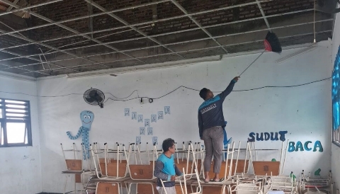 Petugas membersihkan puing plafon ruang kelas SMPN 60 Surabaya yang runtuh akibat tekanan angin.