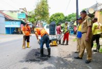 Petugas Satgas Jalan Berlubang melakukan penambalan aspal menggunakan hotmix di salah satu ruas jalan perkotaan di Banyuwangi, Kamis (5/2/2026).