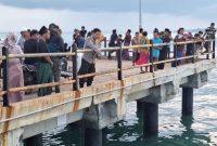 Petugas kepolisian bersama warga memantau area jembatan Pelabuhan Dungkek, Kecamatan Dungkek, Kabupaten Sumenep, lokasi seorang pemuda diduga melompat ke laut, Senin (9/2/2026).