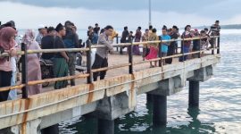 Petugas kepolisian bersama warga memantau area jembatan Pelabuhan Dungkek, Kecamatan Dungkek, Kabupaten Sumenep, lokasi seorang pemuda diduga melompat ke laut, Senin (9/2/2026).