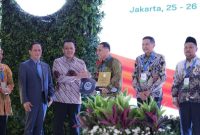 Hanif Faisol Nurofiq menyerahkan penghargaan kepada Wali Kota Surabaya Eri Cahyadi pada Rakornas Pengelolaan Sampah 2026 di Jakarta.