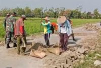 Babinsa Desa Guworejo Koramil 02/Karangmalang Kodim 0725/Sragen Sumartana bersama warga melaksanakan kerja bakti menguruk bahu jalan yang rusak di Desa Guworejo, Kabupaten Sragen, Senin (09/03/2026).