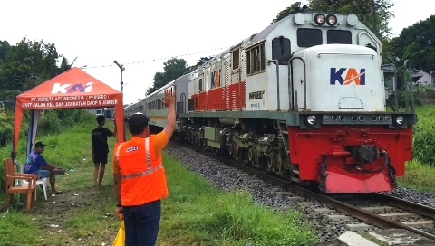 Petugas Jaga Lintasan Ekstra (PJL) berjaga di perlintasan sebidang kereta api tanpa palang pintu di Banyuwangi untuk mengatur lalu lintas dan memastikan keselamatan pengguna jalan selama periode Angkutan Lebaran 2026.