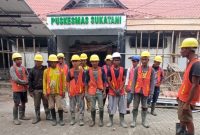 Para pekerja proyek mengikuti briefing dan doa bersama sebelum memulai pekerjaan renovasi Puskesmas Sukatani.