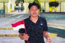Koordinator GPN JATIM Syafiqurrahman dengan bendera dan sebungkusa nasi di tangan.