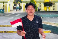 Koordinator GPN JATIM Syafiqurrahman dengan bendera dan sebungkusa nasi di tangan.