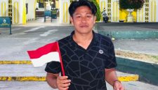 Koordinator GPN JATIM Syafiqurrahman dengan bendera dan sebungkusa nasi di tangan.