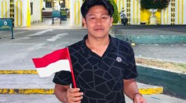 Koordinator GPN JATIM Syafiqurrahman dengan bendera dan sebungkusa nasi di tangan.