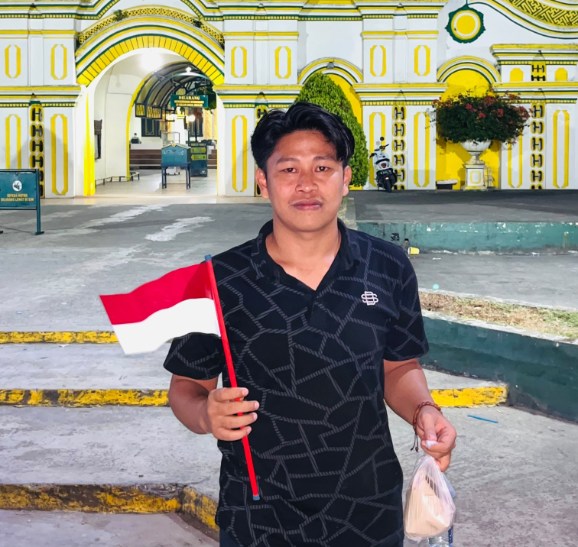 Koordinator GPN JATIM Syafiqurrahman dengan bendera dan sebungkusa nasi di tangan.